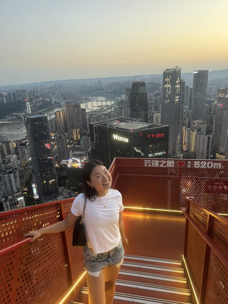 Jasmine Ma standing on a city overlook at sunset