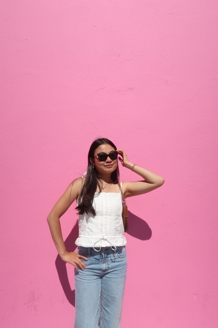 Jasmine Ma in sunglasses in front of a bright pink wall